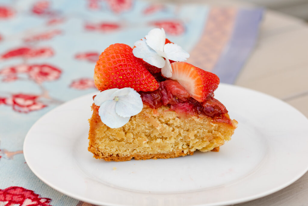 A slice of Strawberry Olive Oil cake baked with our California Olive Oil and topped with strawberry slices and edible flowers