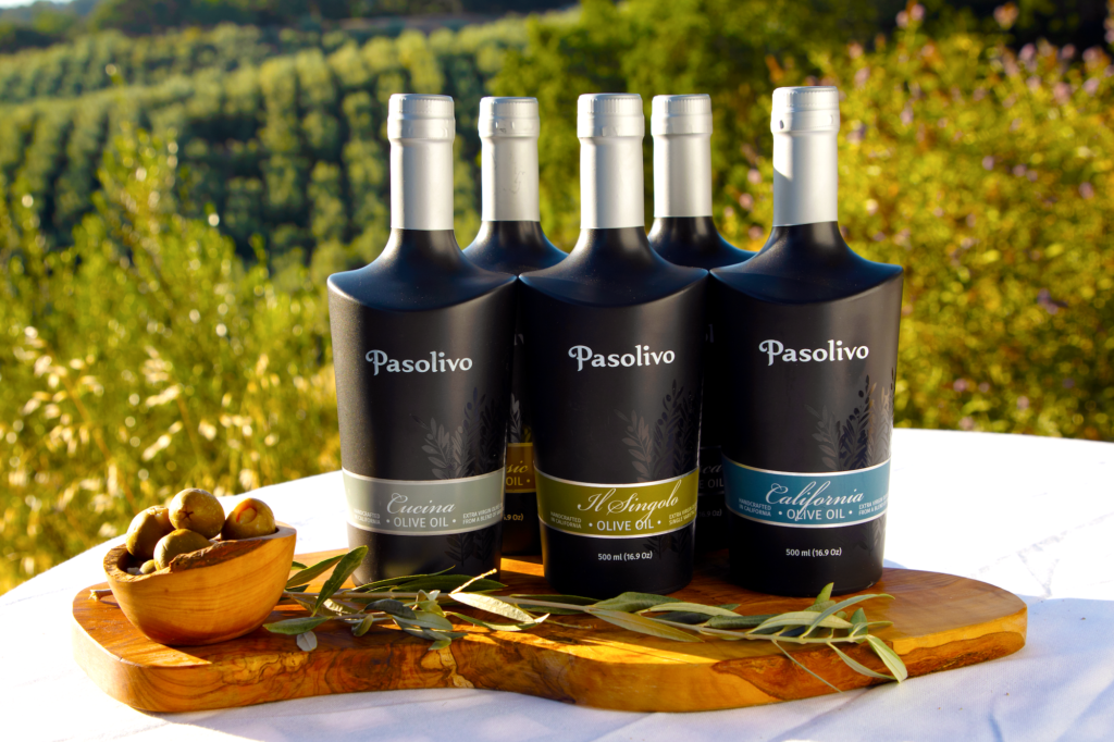 A selection of Pasolivo Olive Oils against a backdrop of sunkissed olive trees