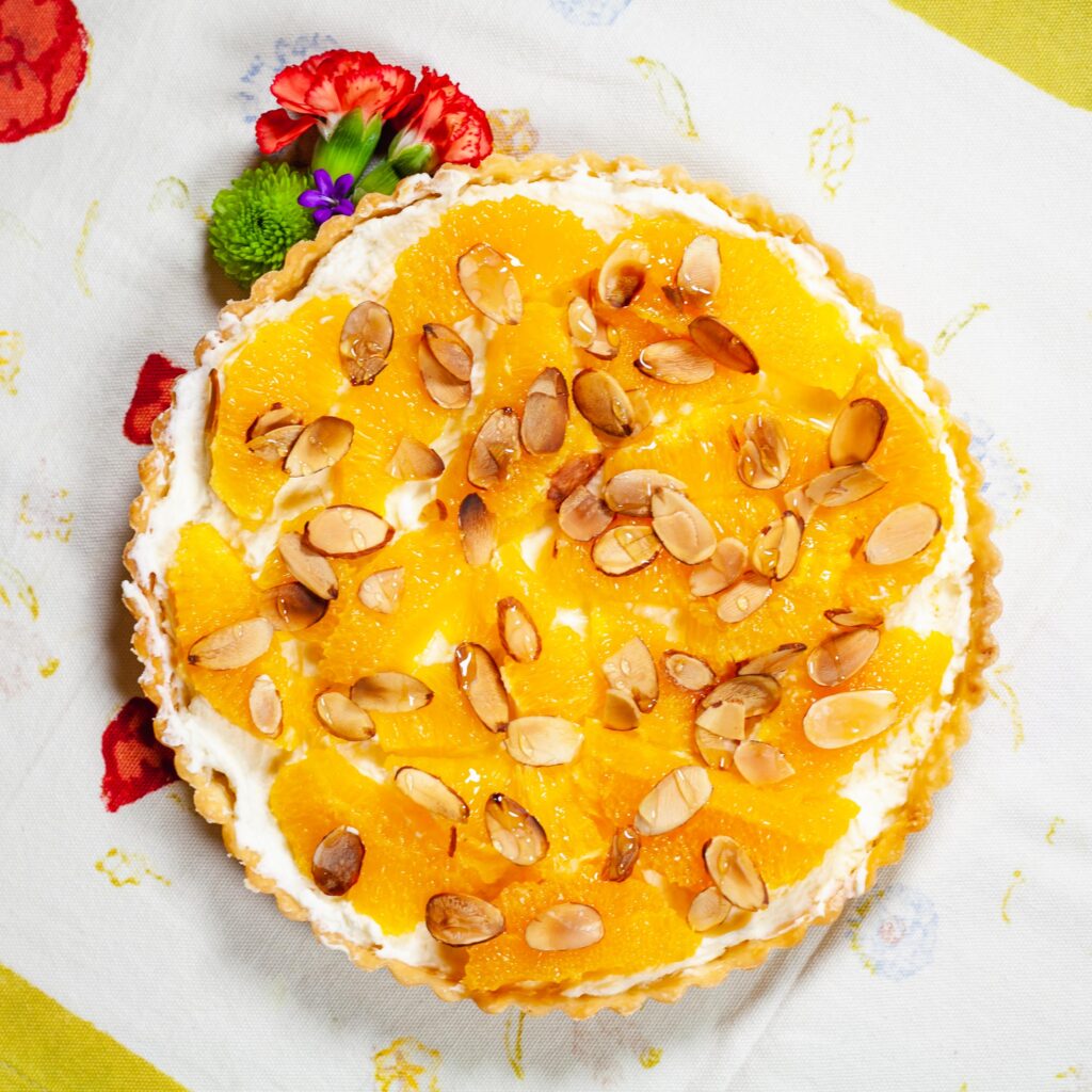 A citrus marzipan tart topped with toasted sliced almonds and baked using Pasolivo olive oil